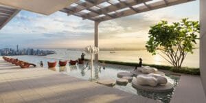 Swimming pool at Keeperz Suites with water play area, lounge seating and panoramic coastal view.